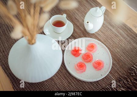 Dessert di gelatina rosa con un set di tè sul tavolo. (messa a fuoco selettiva) Foto Stock