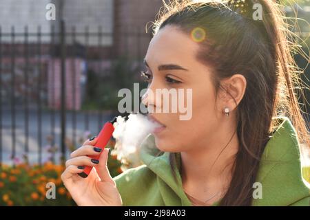 Bella bruna fumo di sigaretta elettronica in luoghi pubblici Foto Stock