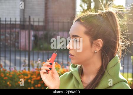 Bella bruna fumo di sigaretta elettronica in luoghi pubblici Foto Stock