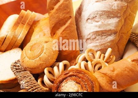 Sfondo culinario con pane, panini, bagel secchi, spighe di grano in un cestino di vimini, vista dall'alto Foto Stock