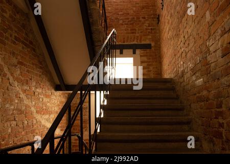 Un ingresso all'interno di una vecchia casa con una scala alla cima e muri in mattoni in Ucraina, una scala in una vecchia casa a più piani, una scala in hou Foto Stock