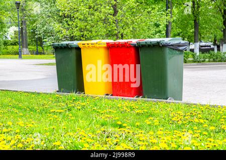 Contenitori in plastica multicolore per la raccolta differenziata dei rifiuti nel parco cittadino. Separare i contenitori per rifiuti in base al tipo di rifiuti Foto Stock