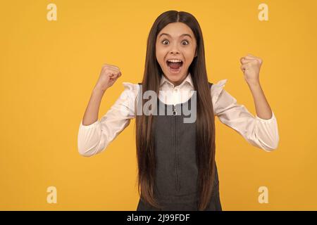 Felice adolescente ragazza vincitore dare il gesto di vittoria celebrando vittoria sfondo giallo, vinto Foto Stock