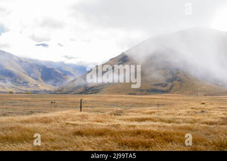 Bassa nube su Burkes rurale e alpino Passo paesaggio di Mackenzie Paese in Canterbury Sud, Nuova Zelanda. Foto Stock