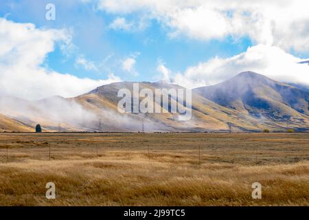 Bassa nube su Burkes rurale e alpino Passo paesaggio di Mackenzie Paese in Canterbury Sud, Nuova Zelanda. Foto Stock