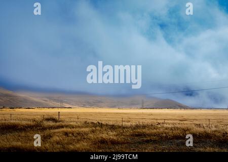 La nuvola bassa si aggira sul paesaggio rurale e alpino del Burkes Pass del Mackenzie Country a Canterbury Sud, Nuova Zelanda. Foto Stock