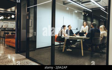 Team di diversi uomini d'affari che hanno una riunione in una sala riunioni trasparente. Gruppo di professionisti aziendali che hanno una discussione durante un briefing. Col Foto Stock