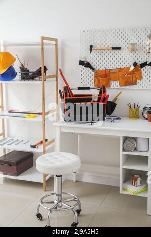 Postazione di lavoro, scaffale e diversi strumenti moderni all'interno dell'officina Foto Stock