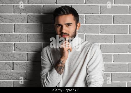 Uomo alla moda su sfondo grigio muro di mattoni Foto Stock