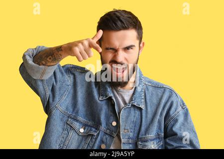 Uomo bearded che punta allo spettatore e che si inbra su sfondo giallo Foto Stock