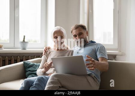 Felice coppia matura entusiasta che usa il notebook a casa Foto Stock