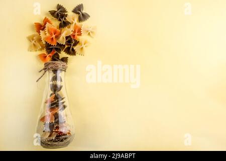 una composizione di pasta sotto forma di bouquet su sfondo giallo. spazio copia Foto Stock