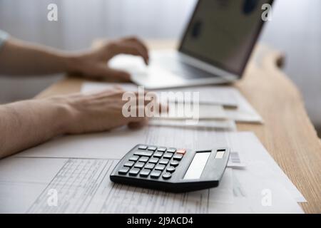 Il giovane contabile lavora con le carte usando la calcolatrice Foto Stock