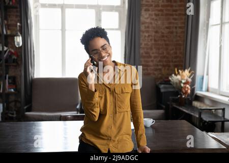 La donna africana in piedi al coperto tiene lo smartphone condurre una piacevole conversazione Foto Stock
