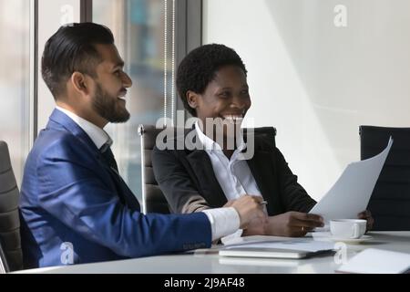 Due compagni di lavoro multirazziale felice ridono brainstorm discutere le idee alla riunione Foto Stock
