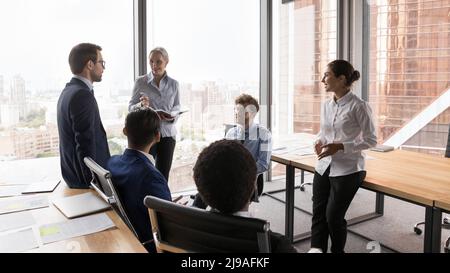 I colleghi multietnici impegnati in briefing aziendali si sono riuniti nella sala riunioni dell'ufficio Foto Stock