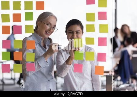 I compagni di lavoro multietnici sviluppano idee di avvio che scrivono su note adesive Foto Stock
