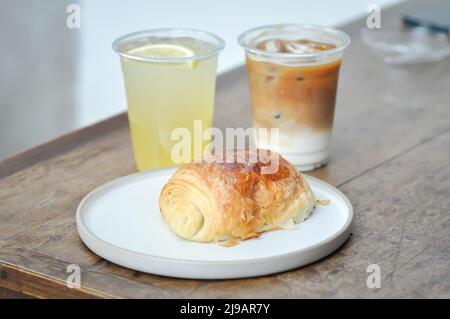 Croissant, croissant alla francese o croissant al cioccolato o pane e caffè e succo di limone per servire Foto Stock