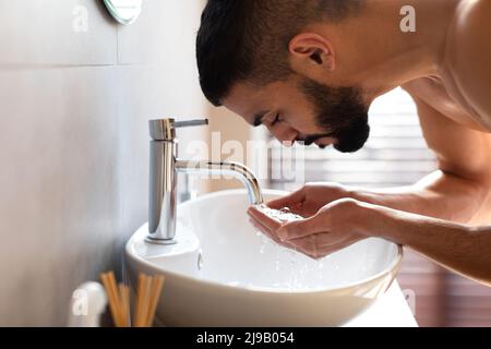 Ritratto di uomo bearded che lava il suo viso al bagno Foto Stock