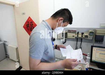 (220522) -- PECHINO, 22 maggio 2022 (Xinhua) -- Mei Xiaodong controlla le prescrizioni mediche per i residenti sotto quarantena domestica nel distretto di Chaoyang a Pechino, capitale della Cina, 21 maggio 2022. Mei Xiaodong, 35 anni, è un operaio governativo del distretto di Chaoyang di Pechino. Mei è stato inviato per unirsi al lavoro del personale di prima linea in una comunità nella lotta contro COVID-19, aiutando i residenti in quarantena a casa di acquistare farmaci per le malattie croniche. I lavoratori, i medici e i volontari della Comunità si assumono la responsabilità di valutare, acquistare e consegnare i medicinali ordinati dai residenti tramite Wecha Foto Stock