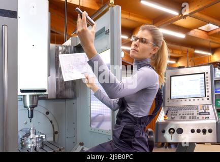 Una tirocinante femminile riceve lezioni tecniche dal suo istruttore. Entrambe le donne lavorano come ingegneri computerizzati di controllo numerico. Foto Stock