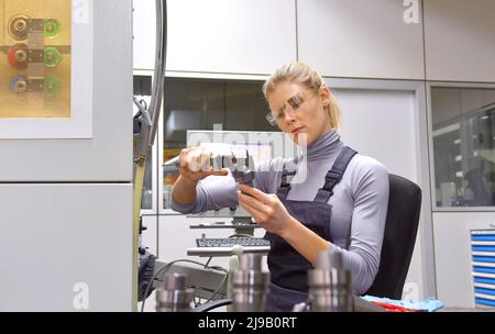 Una tirocinante femminile riceve lezioni tecniche dal suo istruttore. Entrambe le donne lavorano come ingegneri computerizzati di controllo numerico. Foto Stock