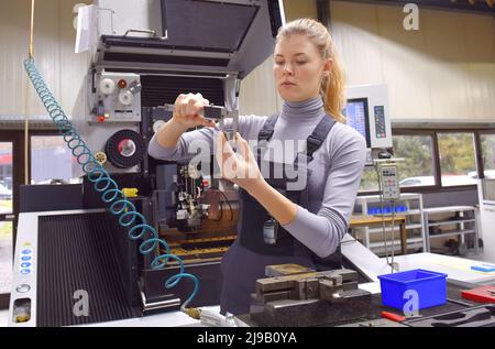 Una tirocinante femminile riceve lezioni tecniche dal suo istruttore. Entrambe le donne lavorano come ingegneri computerizzati di controllo numerico. Foto Stock