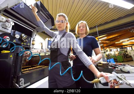 Una tirocinante femminile riceve lezioni tecniche dal suo istruttore. Entrambe le donne lavorano come ingegneri computerizzati di controllo numerico. Foto Stock