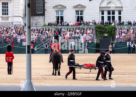 Un membro delle Guardie irlandesi svenisce oggi sotto l’alta temperatura durante la revisione del generale maggiore di Trooping the Color alla Horse Guards Parade Foto Stock