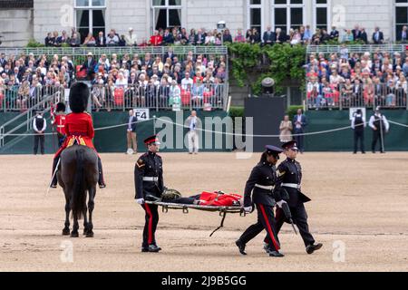 Un membro delle Guardie irlandesi svenisce oggi sotto l’alta temperatura durante la revisione del generale maggiore di Trooping the Color alla Horse Guards Parade Foto Stock