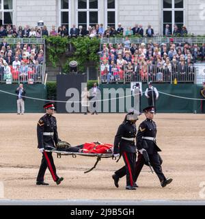 Un membro delle Guardie irlandesi svenisce oggi sotto l’alta temperatura durante la revisione del generale maggiore di Trooping the Color alla Horse Guards Parade Foto Stock