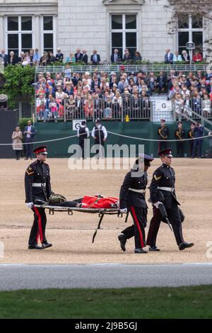 Un membro delle Guardie irlandesi svenisce oggi sotto l’alta temperatura durante la revisione del generale maggiore di Trooping the Color alla Horse Guards Parade Foto Stock