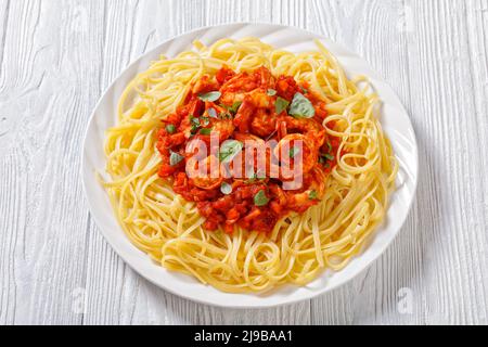 Pasta di gamberi all'aglio piccante con salsa di pomodoro, gamberi in salsa di pomodoro con spaghetti, gamberi alla Marinara su piatto su tavola di legno Foto Stock