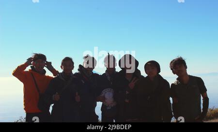 Magelang, Indonesia - 08 06 2019: Silhouette di escursionisti con espressioni felici quando hanno raggiunto la cima del Monte Merbabu sullo sfondo del Th Foto Stock