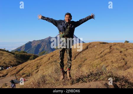 Magelang, Indonesia - 08 06 2019: Una felice espressione da un uomo che salta quando raggiunge la cima del Monte Merbabu Magelang, Giava Centrale, Indonesia Foto Stock