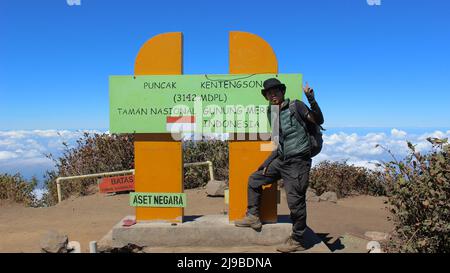 Magelang, Indonesia - 06 08 2019: L'espressione di un uomo in piedi con un cartello in cima a Merbabu Foto Stock