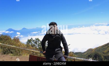 Magelang, Indonesia - 06 08 2019: Uomo che gode la vista dalla cima del Monte Merbabu, Magelang, Giava centrale Foto Stock