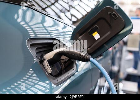 Primo piano dell'auto elettrica con un cavo di ricarica collegato Foto Stock