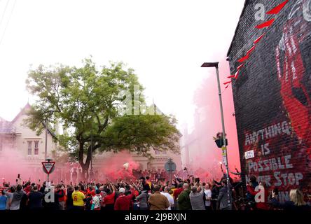 I tifosi di Liverpool si illuminano mentre si riuniscono all'esterno per guardare il bus di squadra arrivare prima della partita della Premier League ad Anfield, Liverpool. Data foto: Domenica 22 maggio 2022. Foto Stock