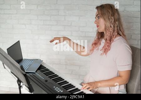 Lezioni di musica remota. Un insegnante di canto registra la lezione su una webcam portatile. Foto Stock