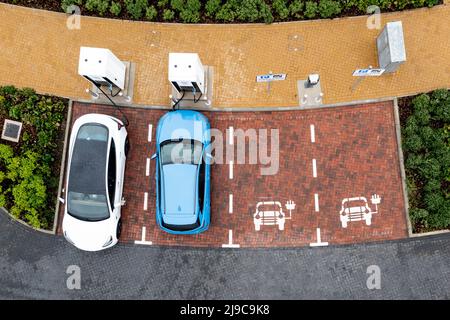 Una vista aerea direttamente sopra le automobili elettriche che sono caricate ad una stazione di servizio dell'autostrada che carica le automobili Foto Stock