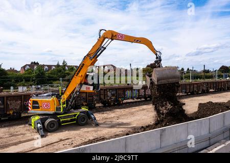PETERBOROUGH, REGNO UNITO - 17 MAGGIO 2022. Una macchina scavatrice per impianti pesanti che scarica il petrolio e la terra dai carri di un treno merci dopo l'ingegneria ferroviaria Foto Stock