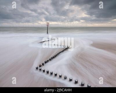 Onde che si lavano su un groyne di legno a Caister-on-Sea a Norfolk. Foto Stock