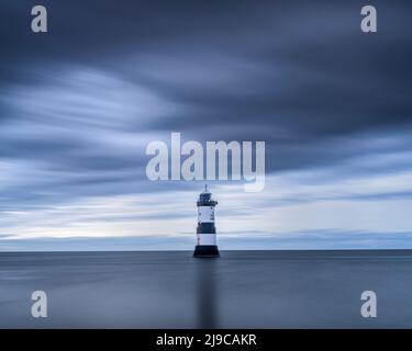 Luce serale a Penmon Point sull'isola di Anglesey con il faro sullo sfondo. Foto Stock