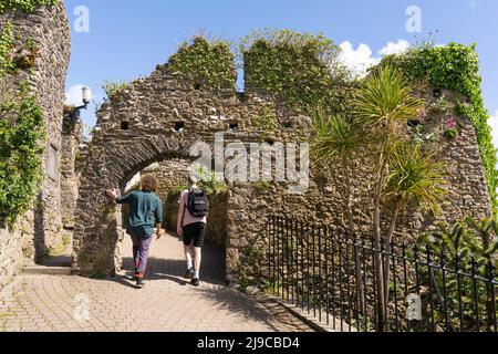 Due visitatori alla città portuale di Tenby camminando attraverso i resti del castello di Tenby porta sulla collina del castello nel mese di maggio. Pembrokeshire, Galles Foto Stock