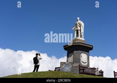 Una femmina turistica che scatta una foto del monumento del Galles al Principe Alberto eretto nel 1865 sulla collina del Castello di Tenby, Galles Foto Stock