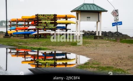 NORWALK, CT, USA - 18 MAGGIO 2022: Vista sulla spiaggia di pascoli di vitello in giornata piovosa con deposito kayak e riflessi in acqua Foto Stock