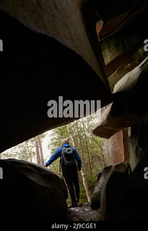 Silhouette di giovane avventuriero in piedi vicino alla roccia Foto Stock