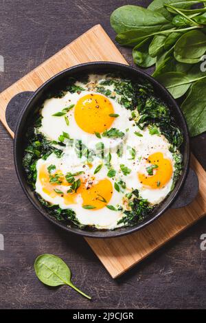 shakshuka verde in una padella in ghisa, uova fritte con spinaci e toast fritto. sana colazione nutriente, Foto Stock
