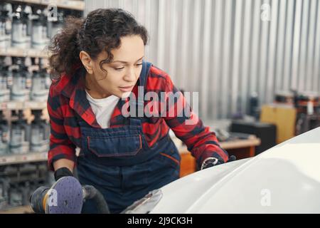 Ragazza allegra master pulizia corpo auto in garage Foto Stock